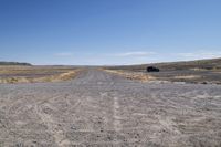 a truck that is parked on a dirt road in a barren landscape with tall grass