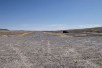 a truck that is parked on a dirt road in a barren landscape with tall grass