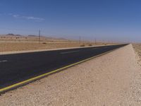 there is a dirt road going through the desert to the horizon, there is no one running on the paved side