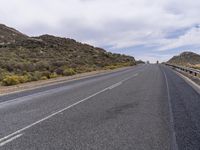 a long, empty desert highway with trees on the side of the road and sky above