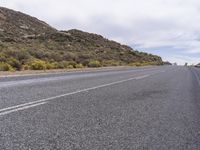 a long, empty desert highway with trees on the side of the road and sky above