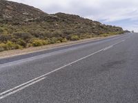 a long, empty desert highway with trees on the side of the road and sky above