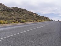 a long, empty desert highway with trees on the side of the road and sky above