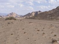 a road running through a desert on a bright day's day with scattered rocks and bushes