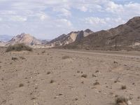 a road running through a desert on a bright day's day with scattered rocks and bushes