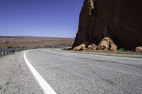 a view of a narrow road in the desert with mountains in the background and two motorcycles parked on both sides