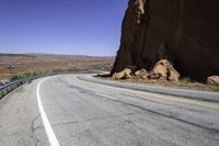 a view of a narrow road in the desert with mountains in the background and two motorcycles parked on both sides