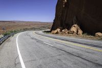 a view of a narrow road in the desert with mountains in the background and two motorcycles parked on both sides