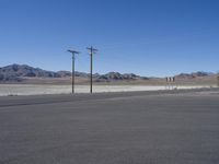 an empty road has no cars on it in this desert area, with power poles