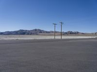 an empty road has no cars on it in this desert area, with power poles