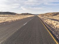 the road is empty and the grass are dead in the dry landscape of the desert