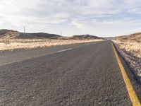 the road is empty and the grass are dead in the dry landscape of the desert