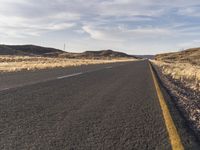 the road is empty and the grass are dead in the dry landscape of the desert