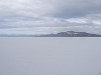 a young girl looking at the horizon on a flat plain with a mountain in the distance