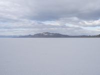 a young girl looking at the horizon on a flat plain with a mountain in the distance
