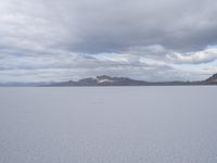 a young girl looking at the horizon on a flat plain with a mountain in the distance