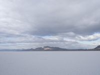 a young girl looking at the horizon on a flat plain with a mountain in the distance