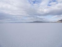 a young girl looking at the horizon on a flat plain with a mountain in the distance