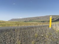 a long road leading through the grass covered hills in the distance is a large river