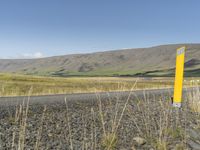 a long road leading through the grass covered hills in the distance is a large river