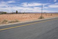 the road is quiet on a sunny day in the desert, with mountains in the distance