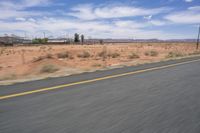 the road is quiet on a sunny day in the desert, with mountains in the distance