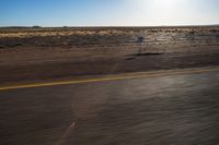 the view from the windshield of an oncoming motorcycle with open desert in background and sunbursted area