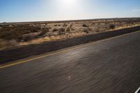 the view from the windshield of an oncoming motorcycle with open desert in background and sunbursted area