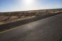 the view from the windshield of an oncoming motorcycle with open desert in background and sunbursted area