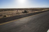 the view from the windshield of an oncoming motorcycle with open desert in background and sunbursted area