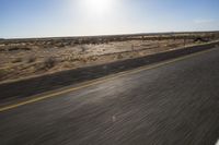 the view from the windshield of an oncoming motorcycle with open desert in background and sunbursted area