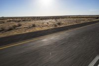 the view from the windshield of an oncoming motorcycle with open desert in background and sunbursted area