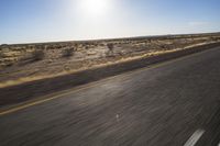 the view from the windshield of an oncoming motorcycle with open desert in background and sunbursted area