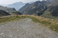 a motorcycle parked on a small mountain side road near mountains with no cars driving on it