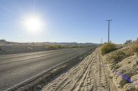 a lone road sits at the edge of the desert with a clear sky in the background