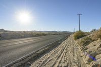 a lone road sits at the edge of the desert with a clear sky in the background