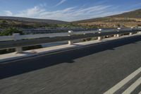 a freeway in the middle of a mountainous area with a train running along it and trucks and buses on the road behind