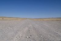 a dirt road in the distance with no cars on it and dry grass near each side