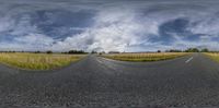 a photo of a wide empty highway with sky in background and clouds hovering overhead of road with two empty roads