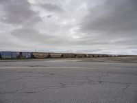 a train passing through an empty street in rural country areas as cloudy skies loom overhead