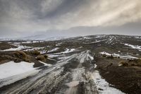 snow covered road on rocky hillside with dark clouds in background with sky covered with snow