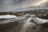 snow covered road on rocky hillside with dark clouds in background with sky covered with snow