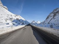 an empty highway is lined with mountains with snow and the road is long and flat