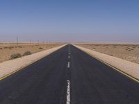 the deserted, empty road leads to a deserted landscape with no trees or grass around