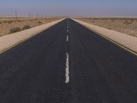 the deserted, empty road leads to a deserted landscape with no trees or grass around