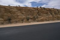 a motorcycle is travelling down the road as it moves by the hill top of a mountain