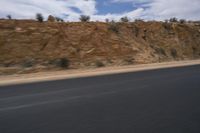 a motorcycle is travelling down the road as it moves by the hill top of a mountain