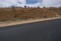 a motorcycle is travelling down the road as it moves by the hill top of a mountain