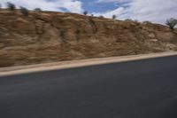 a motorcycle is travelling down the road as it moves by the hill top of a mountain