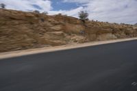 a motorcycle is travelling down the road as it moves by the hill top of a mountain